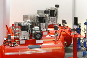 Various red air compressors and equipment in a room.